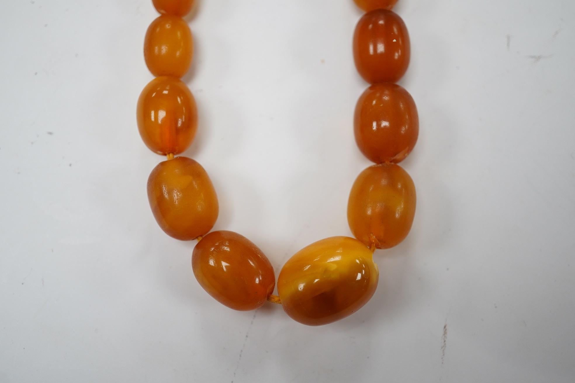 A single strand graduated oval amber bead necklace, 58cm, gross weight 34 grams. Condition - poor to fair